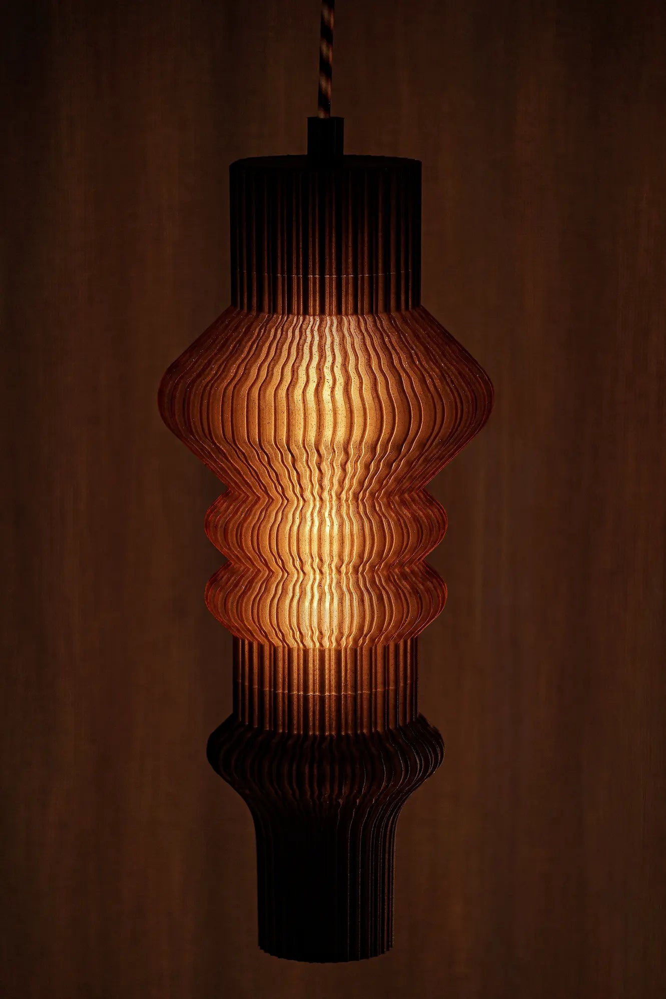 Suspension Vira diffusant une lumière douce à travers une matière biosourcée imprimée en 3D.
